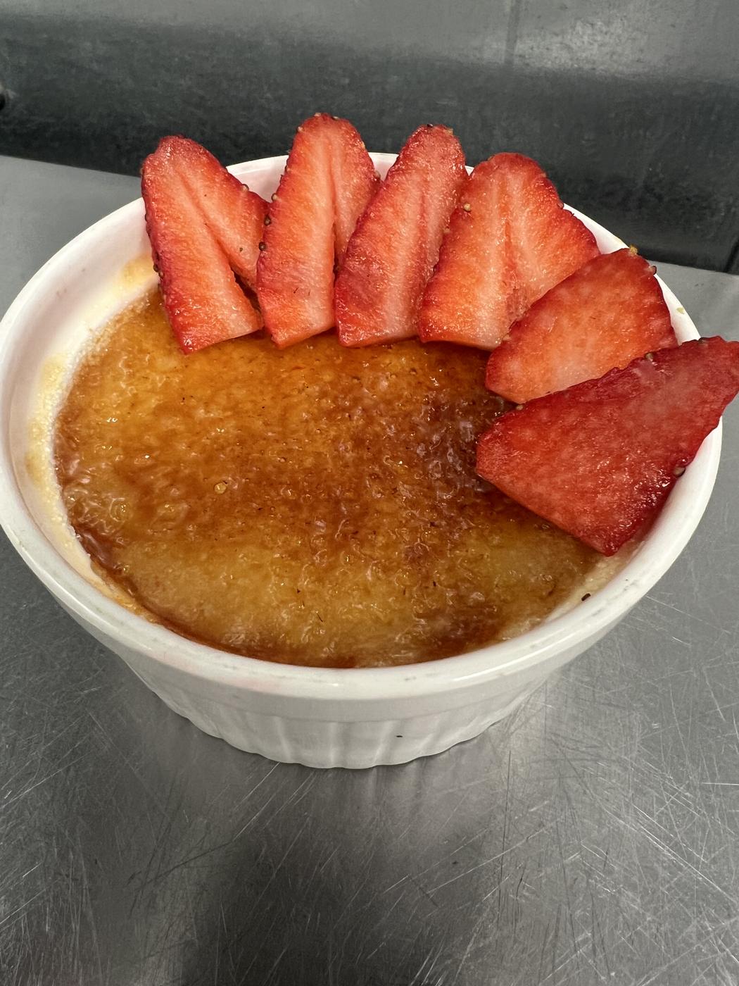 Crème brûlée topped with sliced strawberries