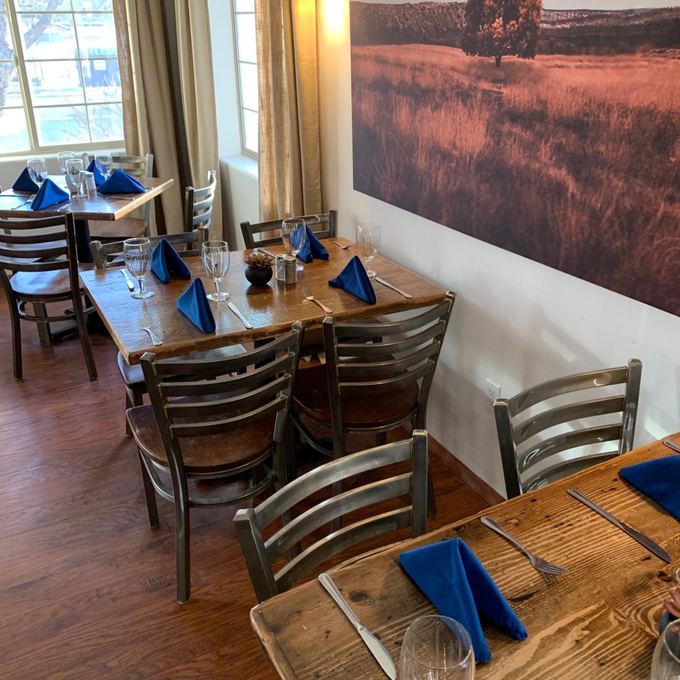 Wine glasses and royal-blue napkins set on reclaimed-wood tables in the dining room