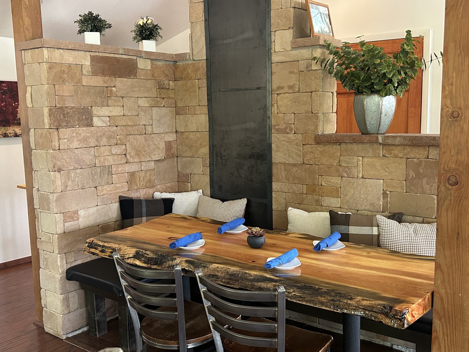 A booth along the stone wall with a live-edge wood table