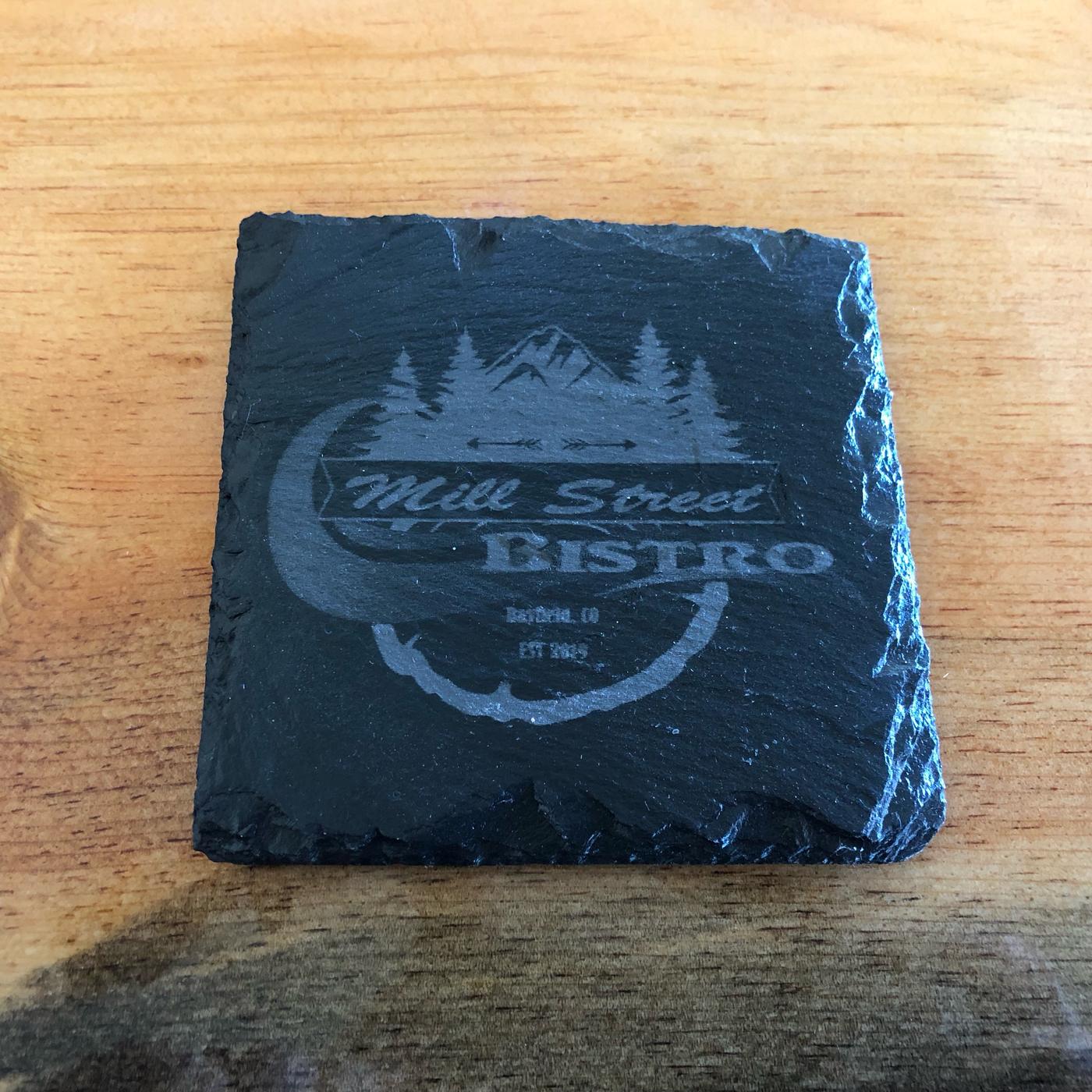 A slate coaster etched with the Mill Street Bistro logo