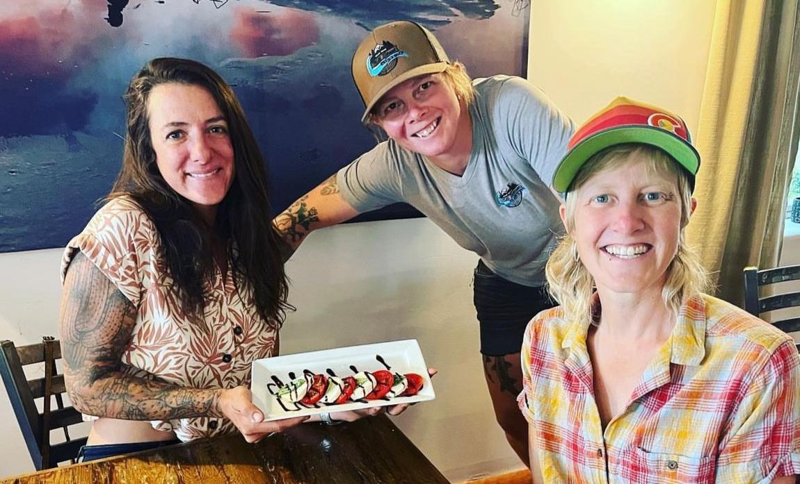 Chef Kelsy Peabody with friends at the Bistro, holding a plate of dessert